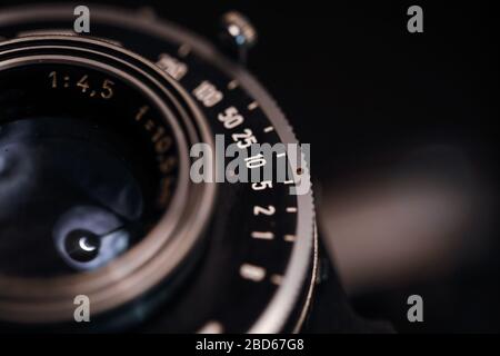 Immagine macro e bassa profondità di campo (messa a fuoco selettiva) con i contrassegni sull'obiettivo di una fotocamera molto vecchia (tempo di esposizione e f-stop). Foto Stock