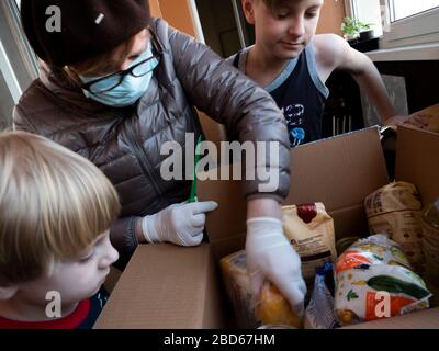 La donna anziana con i suoi nipoti disimballa una scatola di aiuti alimentari nel quadro della campagna "solidarietà e gentilezza Unite" è stata organizzata dal Partito europeo della solidarietà insieme alla Fondazione Petro Poroshenko. Foto Stock