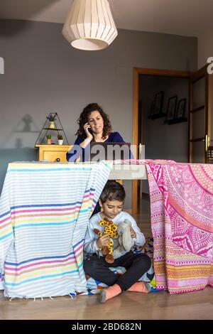 Madre che lavora a casa mentre suo figlio gioca Foto Stock