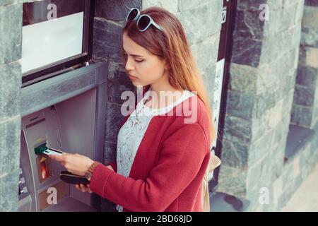 Donna che tira fuori i soldi dalla carta di debito ad un bancomat. La ragazza utilizza la carta di credito per prelevare presso il terminale di cassa della Banca Foto Stock
