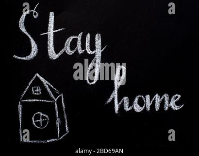 Disegno con gesso su una lavagna nera, casa e testo rimanere a casa. Concetto di protezione dai virus Foto Stock