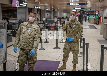 I soldati della Guardia Nazionale dell'Esercito delle Hawaii aspettano di schermare i passeggeri in partenza all'Aeroporto Internazionale Daniel K. Inouye il 6 aprile 2020 a Honolulu, Hawaii. I soldati assistono il personale dei pompieri dell'aeroporto con lo screening del 100% dei viaggiatori in arrivo e in partenza, per includere i viaggi tra le isole. Foto Stock