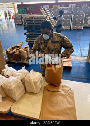 Guardia Nazionale dell'Esercito di New York SPC. Standley Jean Baptiste, pacchetti pasti presso il sito di distribuzione di cibo Bronx nel Centro ricreativo Hunts Point 6 aprile 2020 a Bronx, New York. I pasti sono distribuiti ai cittadini che sono messi in quarantena e non possono lasciare le loro case. Foto Stock