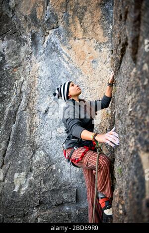 Donna che raggiunge per la mano successiva tenere mentre arrampicata su roccia. Foto Stock