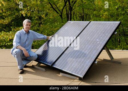 Uomo con pannelli solari sul tetto della casa Foto Stock