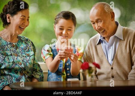 Nonni che giocano le carte con la loro nipote. Foto Stock