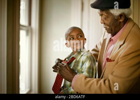 Nonno che aiuta suo nipote a vestirsi. Foto Stock