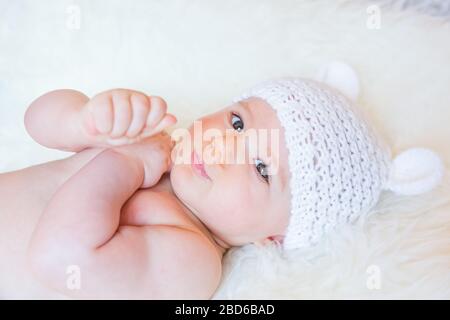 Cute Baby Girl sorridente e che indossa un cappello da orso morbido in maglia Foto Stock