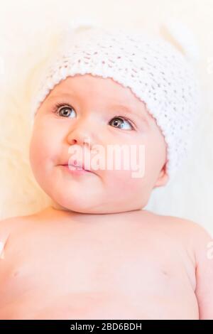 Cute Baby Girl sorridente e che indossa un cappello da orso morbido in maglia Foto Stock