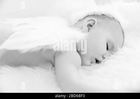 Il bambino dorme tranquillamente mentre indossa le ali dell'angelo e Halo Foto Stock