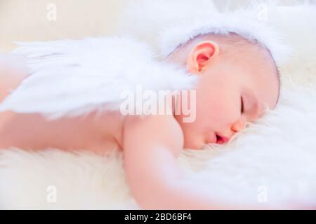 Il bambino dorme tranquillamente mentre indossa le ali dell'angelo e Halo Foto Stock