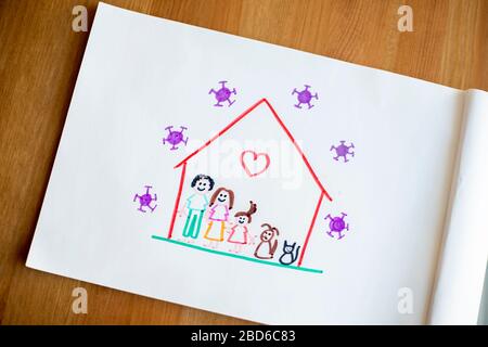 Disegno semplice del bambino su sfondo di legno, rappresentando lei e la sua famiglia e gli animali domestici felici a casa durante il blocco del covid-19 per la pandemia del coronavirus. Foto Stock
