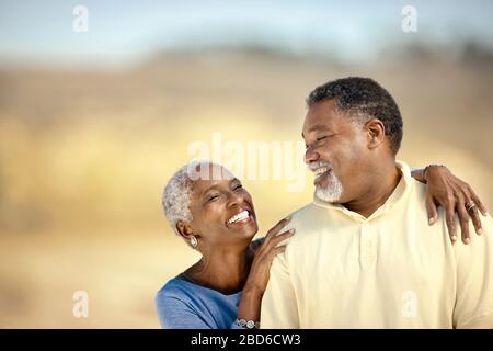 Sorridente coppia senior felicemente in piedi su una spiaggia. Foto Stock