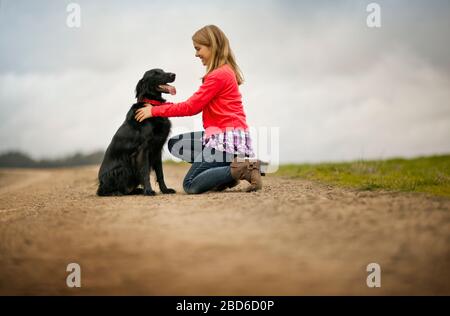 Sorridente ragazza adolescente giocando con il suo cane. Foto Stock