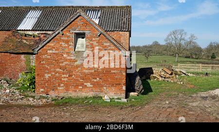 Un edificio di fattoria e fienile derelict con un tetto di tegole collassato Foto Stock