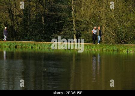Wanstead Park, Londra, Regno Unito - 07 aprile 2020: Le persone camminano a Wanstead Park mentre osservano le distanze sociali in un pomeriggio soleggiato di martedì durante il blocco britannico. Il governo ha consigliato al pubblico di rimanere a casa in tutto il Regno Unito a causa della pandemia Covid-19, ma per viaggi essenziali per le basi e l'esercizio fisico. Foto: David Mbiyu/ Alamy Live News Foto Stock
