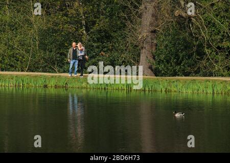 Wanstead Park, Londra, Regno Unito - 07 aprile 2020: Le persone camminano nel Wansteda Park mentre osservano le distanze sociali in un pomeriggio soleggiato di martedì durante il blocco britannico. Il governo ha consigliato al pubblico di rimanere a casa in tutto il Regno Unito a causa della pandemia Covid-19, ma per viaggi essenziali per le basi e l'esercizio fisico. Foto: David Mbiyu/ Alamy Live News Foto Stock