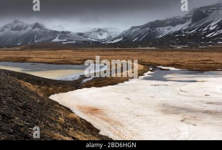 Tipico islandese drammatico paesaggio con lago ghiacciato e montagne coperte di neve in Islanda Foto Stock