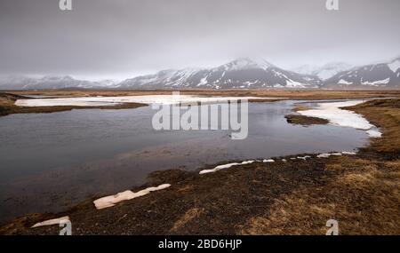 Tipico islandese drammatico paesaggio con lago ghiacciato e montagne coperte di neve in Islanda Foto Stock