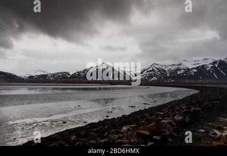 Tipico islandese drammatico paesaggio con lago ghiacciato e montagne coperte di neve in Islanda Foto Stock