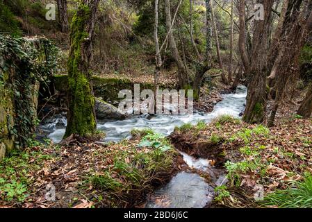 Bellissimo ponte medievale in pietra di Milia con fiume pieno d'acqua che scorre ai monti Troodos a Cipro Foto Stock