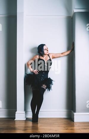 Donne che posano in un alcova con un corsetto nero, tutu e sopra le calze del ginocchio Foto Stock