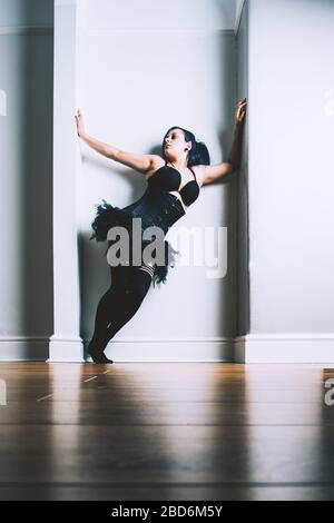 Donne che posano in un alcova con un corsetto nero, tutu e sopra le calze del ginocchio Foto Stock