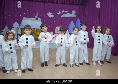 I bambini sono vestiti da pupazzi di neve. I partecipanti all'asilo prendono parte a un evento di Capodanno. Carino ragazzi vestiti in costumi festosi di Babbo Natale Foto Stock