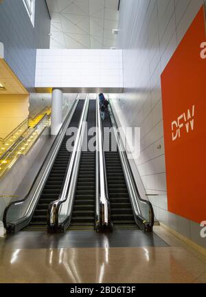 Pochi passeggeri su una scala mobile all'Aeroporto Internazionale di Dallas Fort Worth durante la pandemia Coronavirus COVID-19, altrimenti un aeroporto molto trafficato. Foto Stock