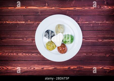 Piatto con gnocchi orientali colorati e salse su fondo in legno. Vista dall'alto Foto Stock