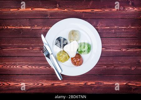 Piatto con gnocchi orientali colorati, salse e posate su fondo in legno. Vista dall'alto Foto Stock