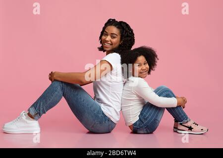 Little Black Girl e la sua mamma seduto sul pavimento e sorridente Foto Stock