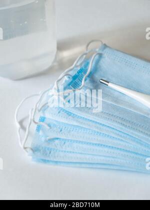 Le maschere mediche proteggono contro la diffusione di coronavirus e un termometro a primo piano su sfondo bianco. Concetto diffuso virus covid-19 Foto Stock