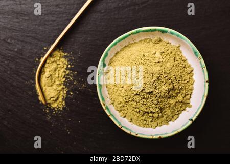 Cucchiaio per tè matcha e pouder verde in speciali ceramiche sauser. Sfondo nero. Foto in stile piatto. Il fuoco è sul pouder di matcha. Foto Stock
