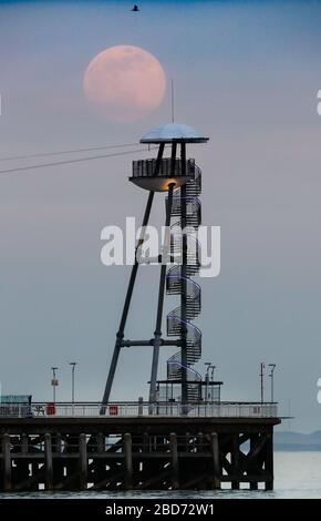 Bournemouth, Regno Unito. 7 aprile 2020. La Super Pink Moon sorge sopra il molo di Bournemouth a Dorset. Credit: Richard Crease/Alamy Live News Foto Stock