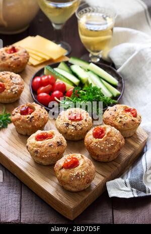Muffin con formaggio, formaggio casolare e pomodori, verdure e formaggi serviti con vino. Foto Stock