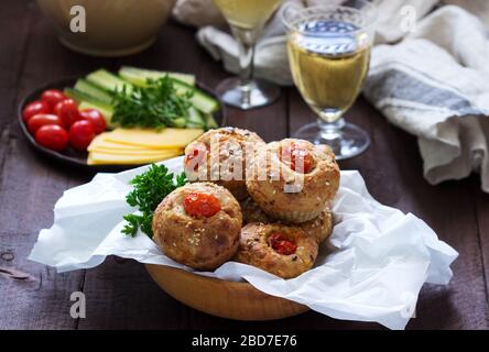 Muffin con formaggio, formaggio casolare e pomodori, verdure e formaggi serviti con vino. Foto Stock