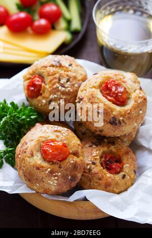 Muffin con formaggio, formaggio casolare e pomodori, verdure e formaggi serviti con vino. Foto Stock