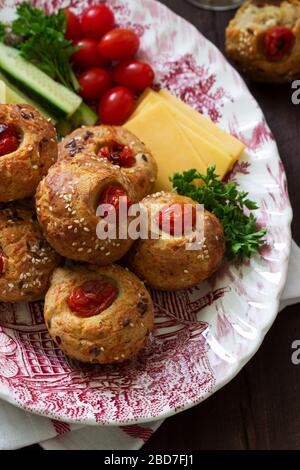 Muffin con formaggio, formaggio casolare e pomodori, verdure e formaggi serviti con vino. Foto Stock