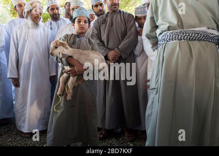 Uomini e ragazzi di Omani apprendisti e si contrattano per il bestiame al mercato del bestiame del venerdì nell'antico suk di Nizwa in Oman Foto Stock