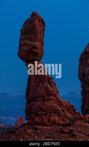 Balanced Rock in Arches National Park al crepuscolo con le montagne la SAL sullo sfondo, Utah, USA. Foto Stock