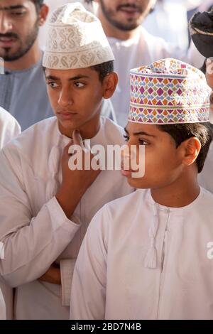 Uomini e ragazzi di Omani apprendisti e si contrattano per il bestiame al mercato del bestiame del venerdì nell'antico suk di Nizwa in Oman Foto Stock