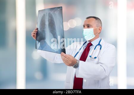 Medico che indossa una maschera mentre regge un concetto di radiografia polmonare, coronavirus e polmonite Foto Stock