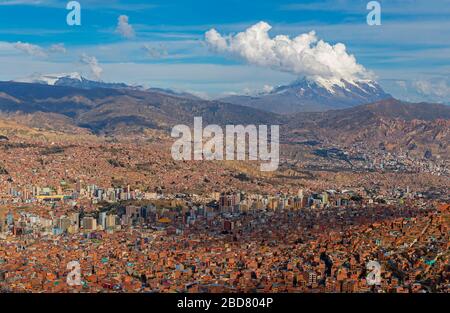 La vista aerea dello skyline di la Paz ad alta quota con il vulcano Illimani, la cima delle Ande sullo sfondo, Bolivia. Foto Stock