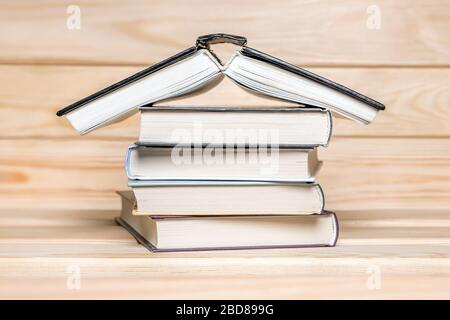 Concetto di soggiorno a casa. Casa fatta con libri impilati su sfondo di legno. Pila di libri. Concetto di istruzione. Pila di libri in forma di un edificio. Libro Foto Stock