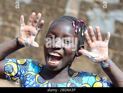 Splendida ragazza nera africana felice di lavarsi le mani con igienizzante, sapone e acqua Foto Stock