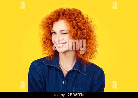 Verricello. Closeup donna redhead capelli ricci sorridendo occhio lampeggiante a voi fotocamera isolato su sfondo giallo. Immagini di vita felice, felicità Foto Stock