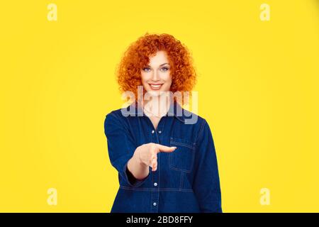 Affare. Ritratto closeup giovane riccio rosso riccio sorridente donna, studente, agente del servizio clienti che ti dà stretta di mano isolato sfondo muro giallo. Foto Stock