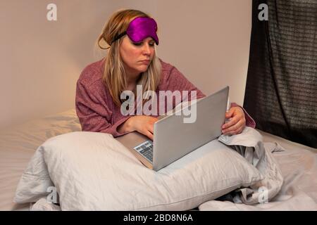 donna che osserva rumpled che porta il contrassegno dell'occhio e l'accappatoio che funzionano nel letto Foto Stock