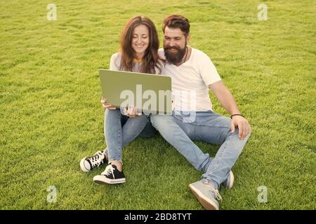 Verso la conoscenza. Lavorare sul computer nel parco. Uomo e donna navigare su Internet su notebook. Vita degli studenti. Shopping online. Comunicazione online. Felice coppia utilizzare il computer portatile su erba verde. Foto Stock